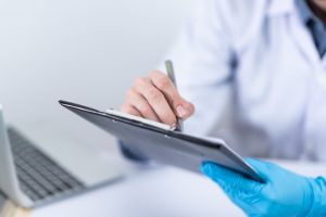doctor with one blue glove making note