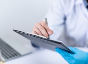 doctor with one blue glove making note