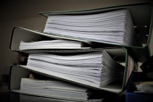 stack of thick three ring binders full of papers